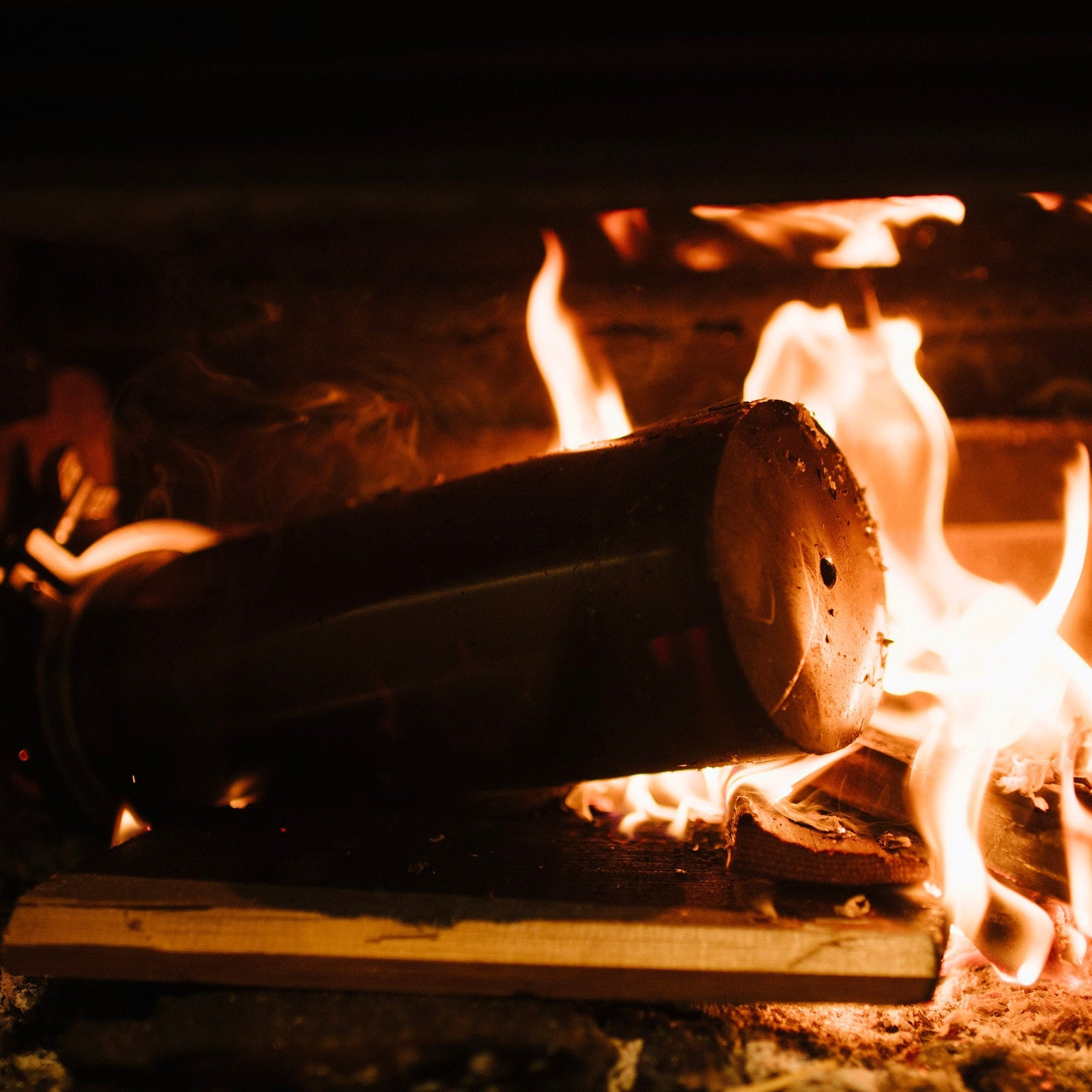 Firewood burning in a fireplace with flames and smoke