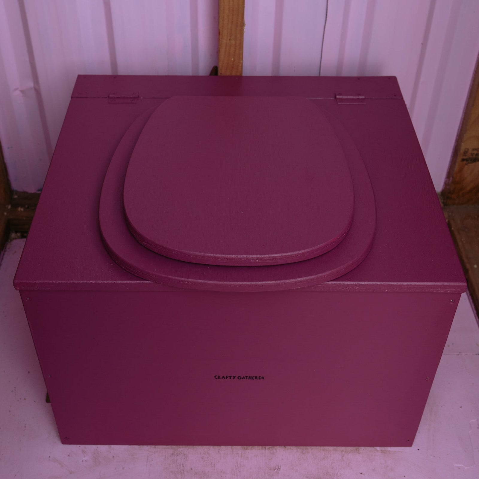 Magenta composting toilet and tank cover on a white background
