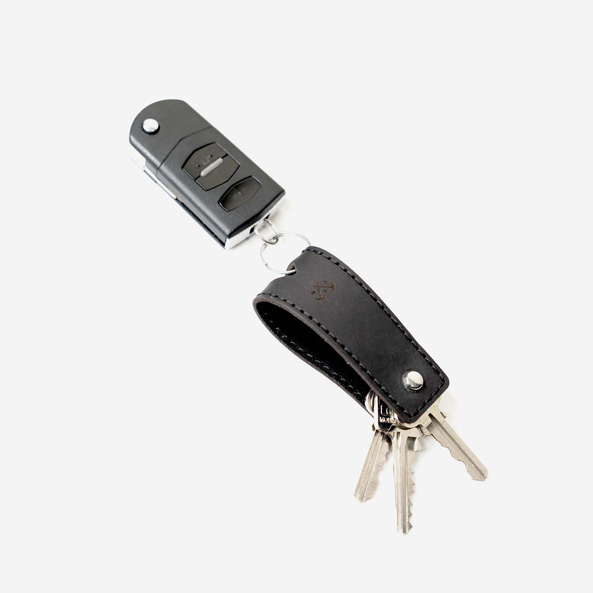 Keychain with black leather holder and silver keys on a white background