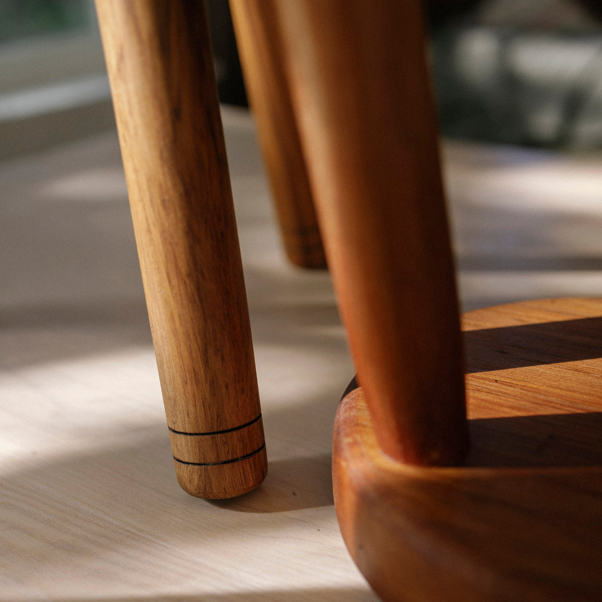Close-up of a wooden chair leg on a light wood floor