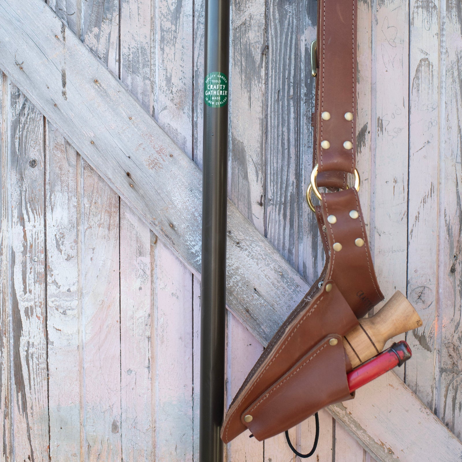 Black metal tool with a brown leather holster attached, against a wooden background