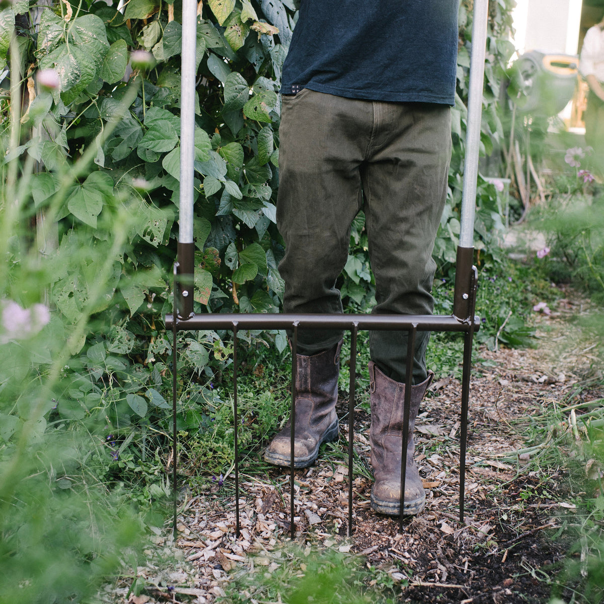 Person standing on a metal garden Boardfork in a garden setting