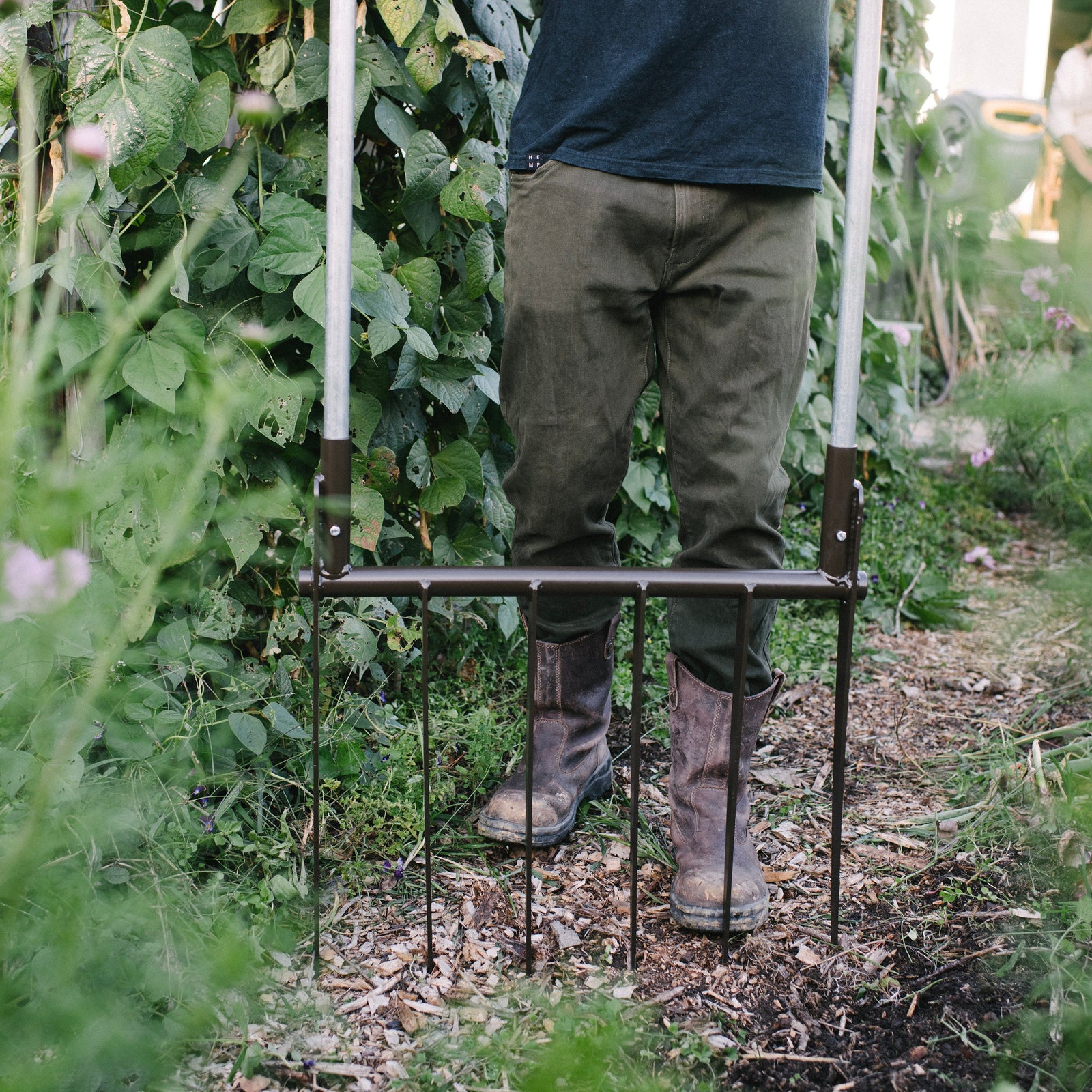 Person standing on a metal garden Boardfork in a garden setting