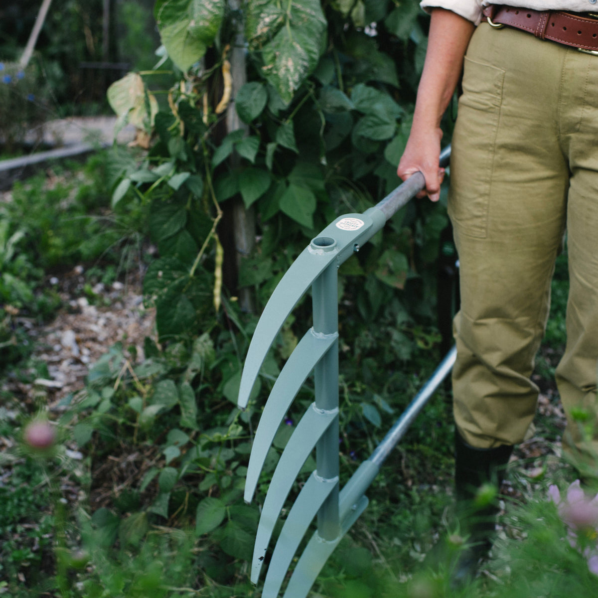 Person holding a garden tool in a garden setting