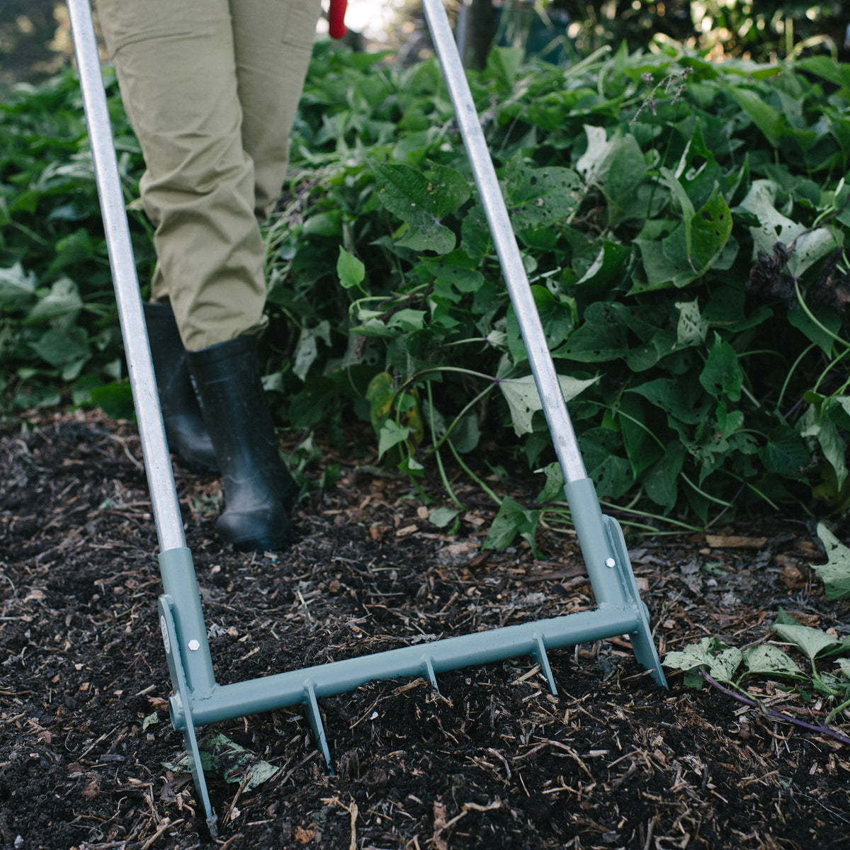 Person using a boardfork in a garden setting with greenery in the background