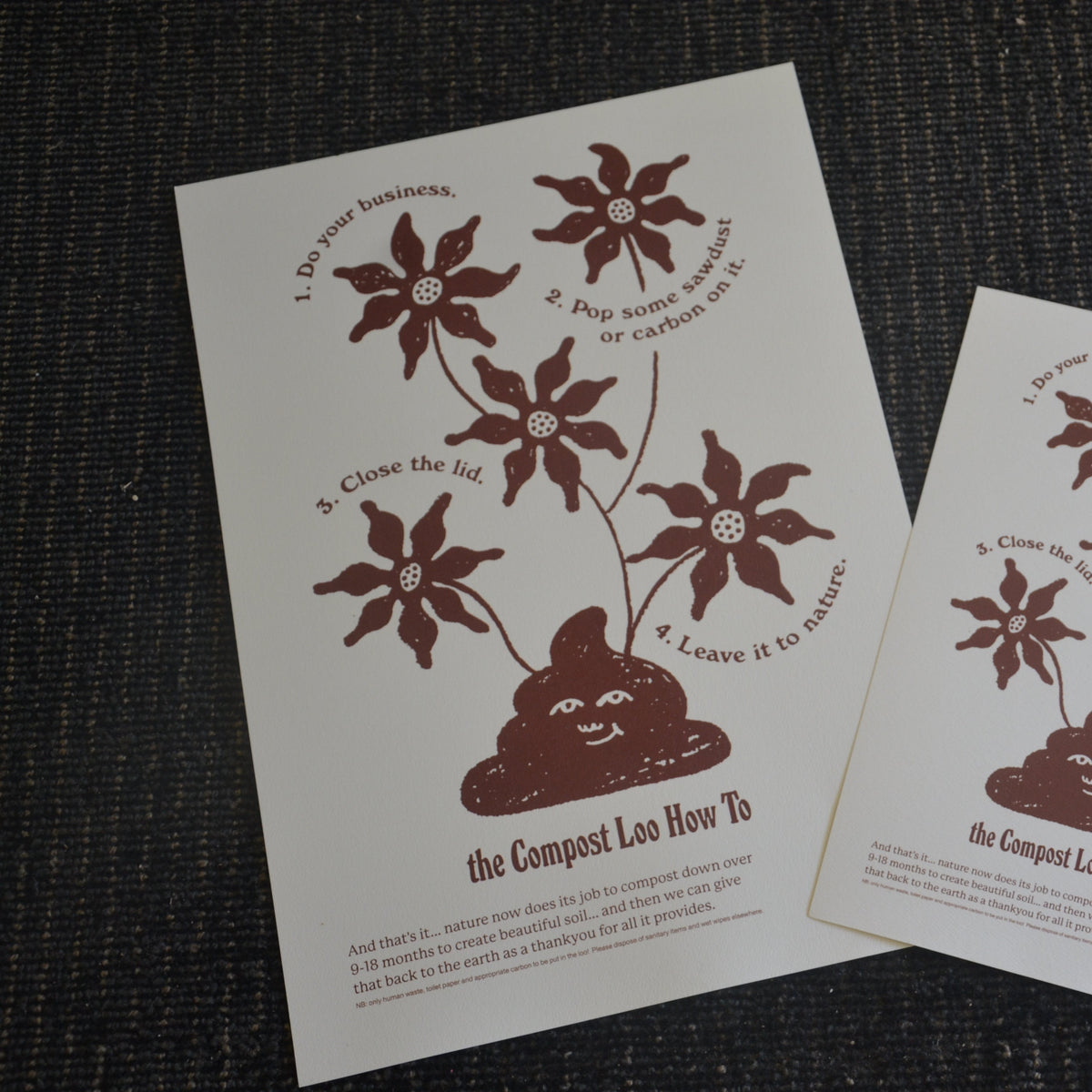 Two printed sheets with composting toilet instructions and illustrations on a textured surface.