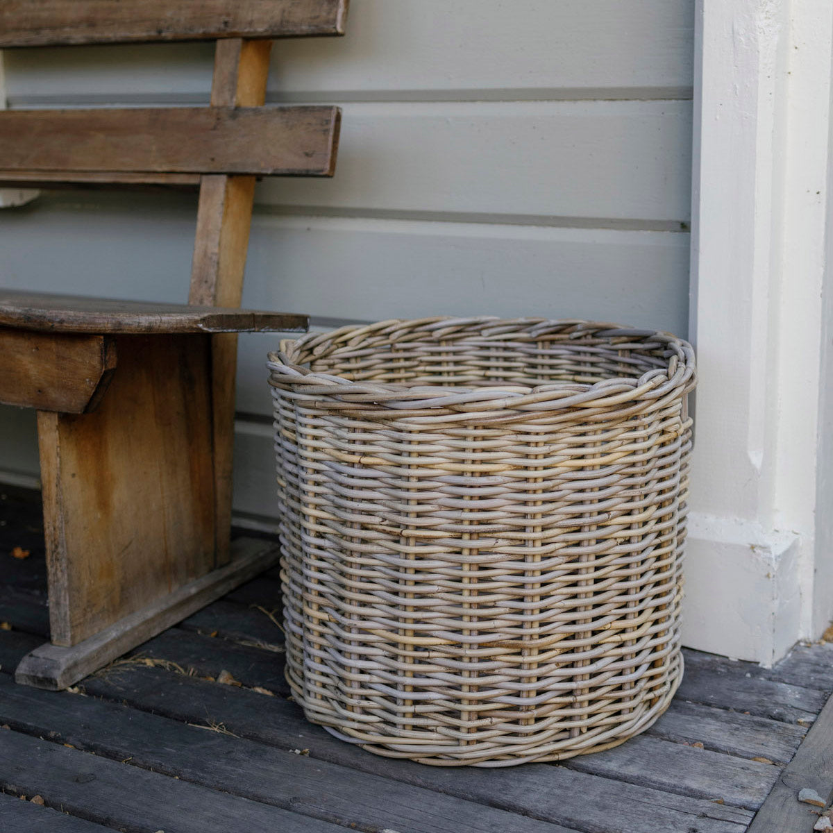 Wicker basket on a wooden deck next to a wooden bench