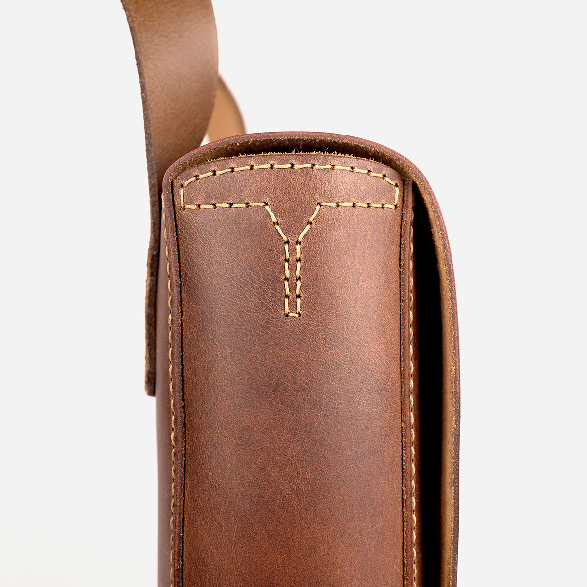 Brown leather bag with gold stitching on a white background