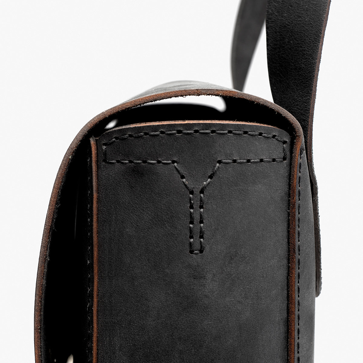 Close-up of a black leather bag with visible stitching on a white background