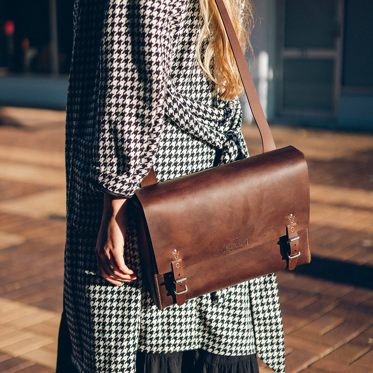 Person holding a brown leather satchel on there way to work.