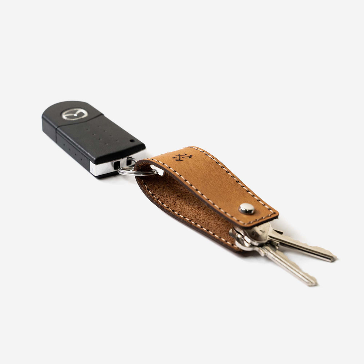 Keychain with car key fob and brown leather strap on a white background