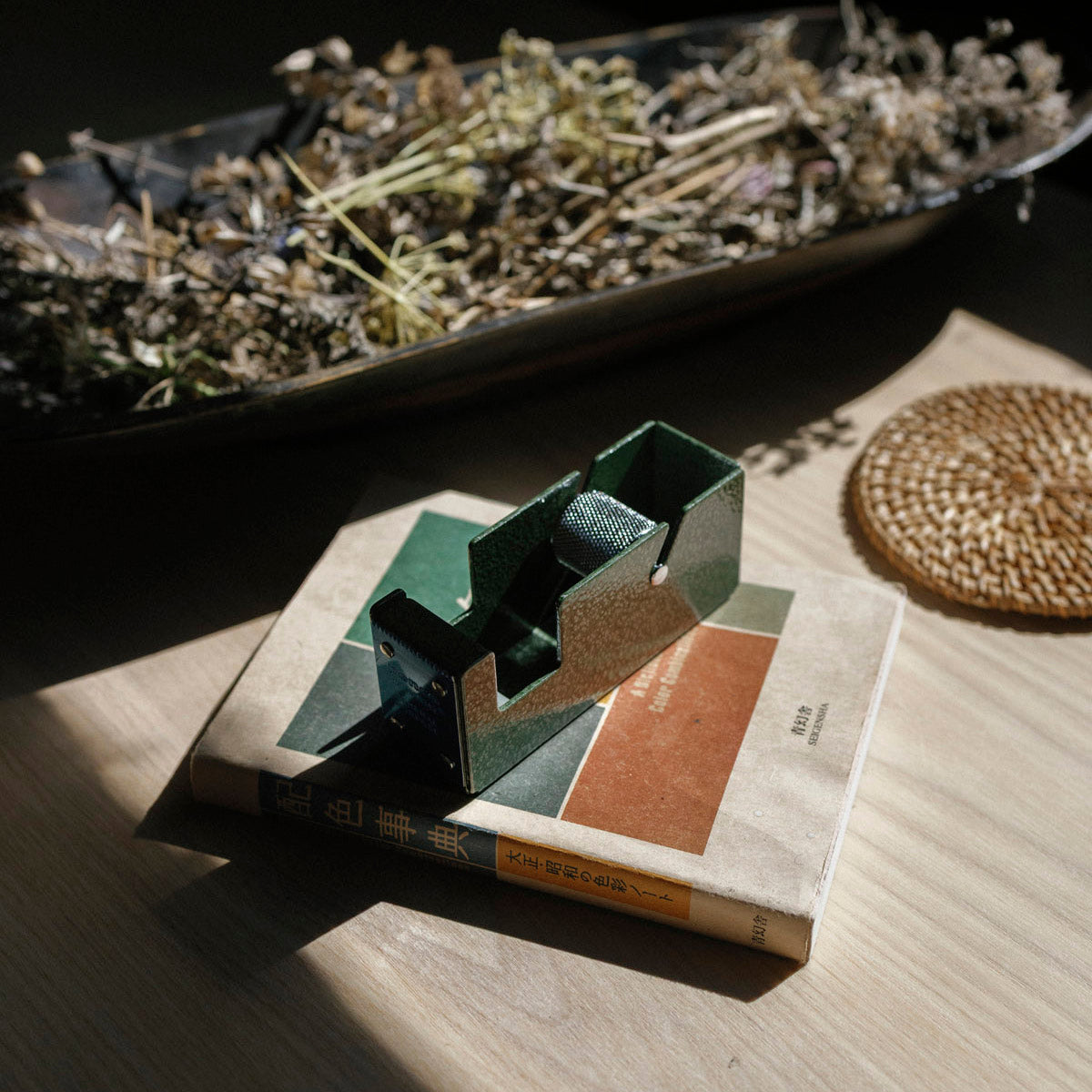 Metal tape dispenser on a book with dried herbs in the background