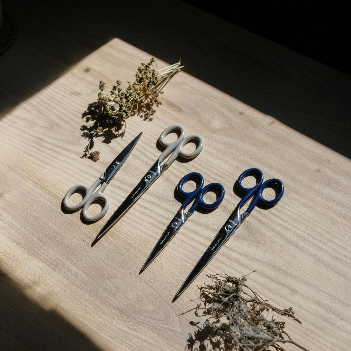 Set of scissors on a wooden surface with dried herbs