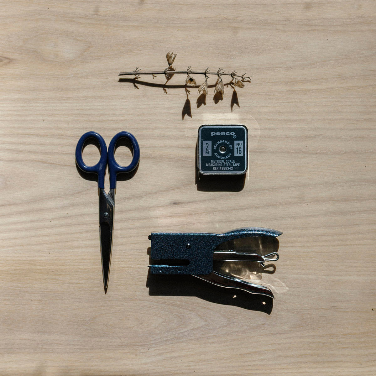 Scissors, stapler, and tape measure on a wooden surface