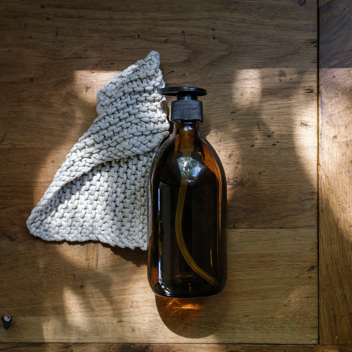 Two glass bottles with black pumps on a windowsill with a textured glass window.