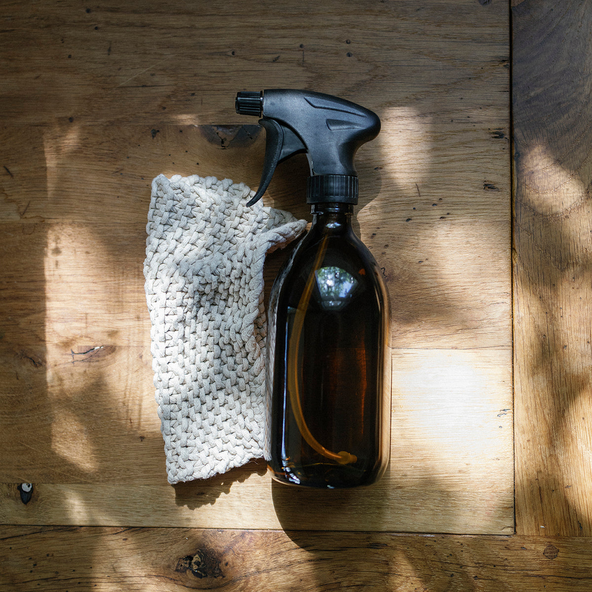 Clear reusable Amber spray bottle with black nozzle on a wooden surface