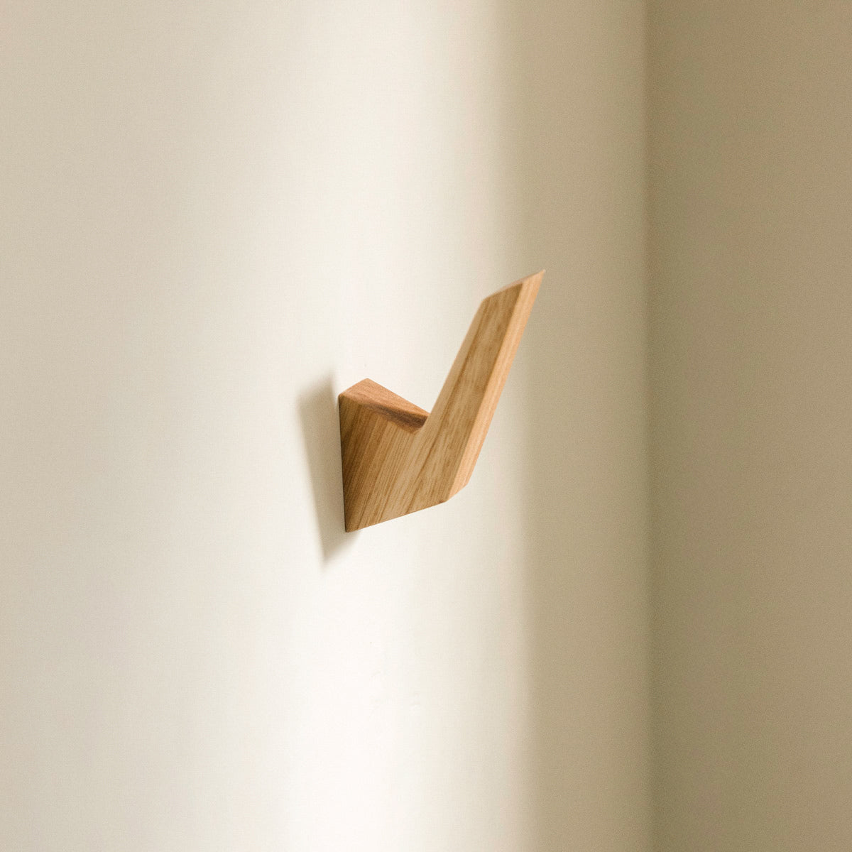 Wooden geometric wall hook on a beige wall