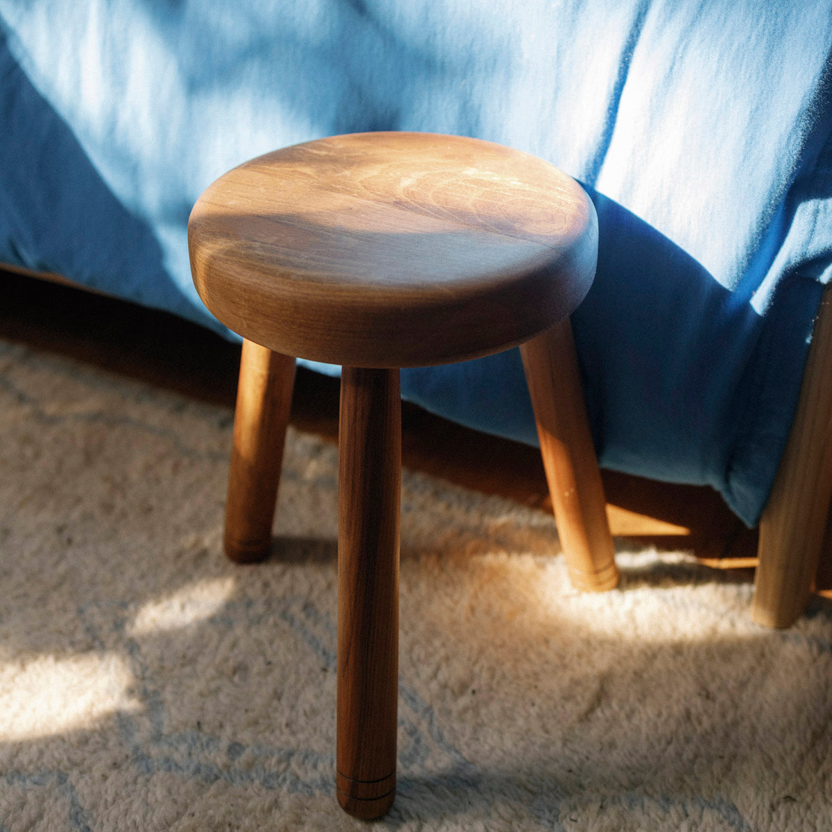Wooden stool with a blue blanket in the background